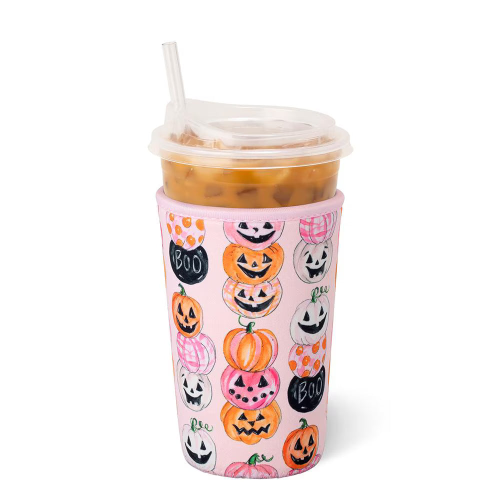 A pink insulated travel tumbler with a clear lid and straw, decorated with a pattern of hand-drawn orange, pink, and white pumpkins and black &