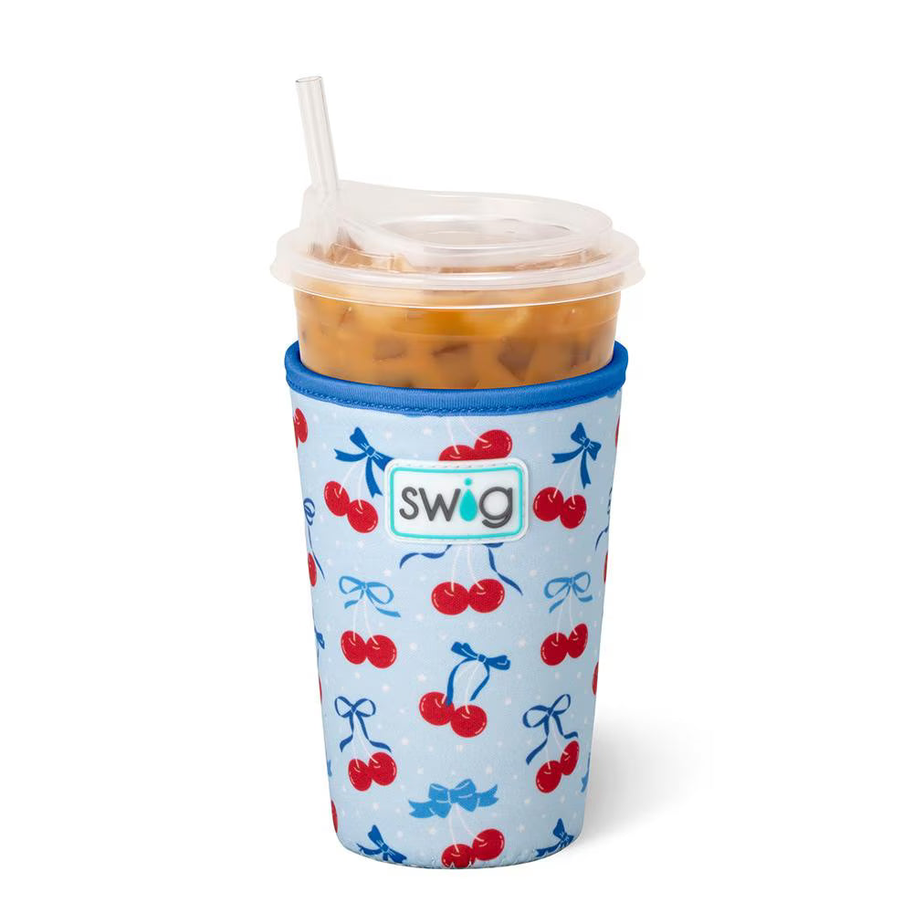 Swig Cherry Pop Medium Iced Cup Coolie featuring a cherry and blue bow print on a light blue background for 22 oz reusable cold cups.