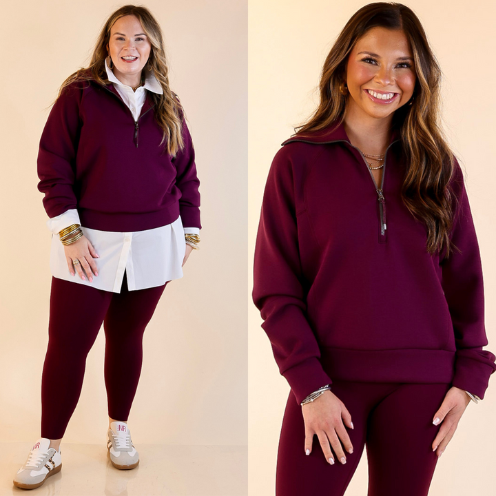 Models are wearing SPANX Air Essentials Half Zip in Plum Berry Maroon on a beige background.