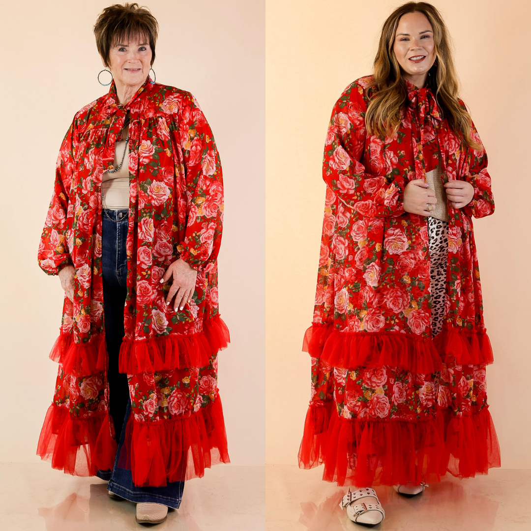 Models are wearing Neck Tie Closure Red Rose Floral Drape Statement Kimono Cape in Red with Jeans against a beige backdrop.