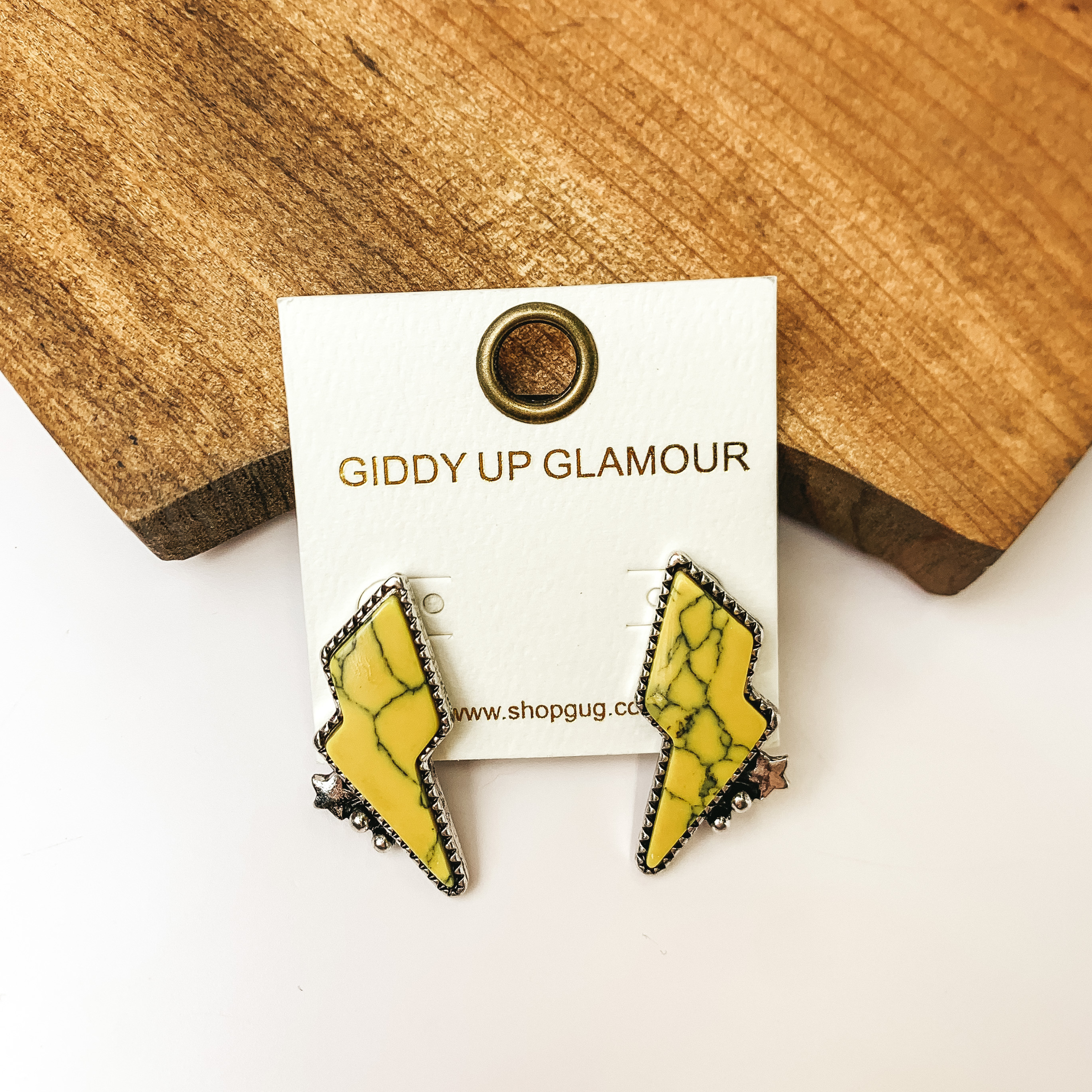 Driving Down Lightning Bolt Stone Post Earrings in Yellow with Silver Detailing. Pictured on a white background with the earrings sitting against a piece of wood.