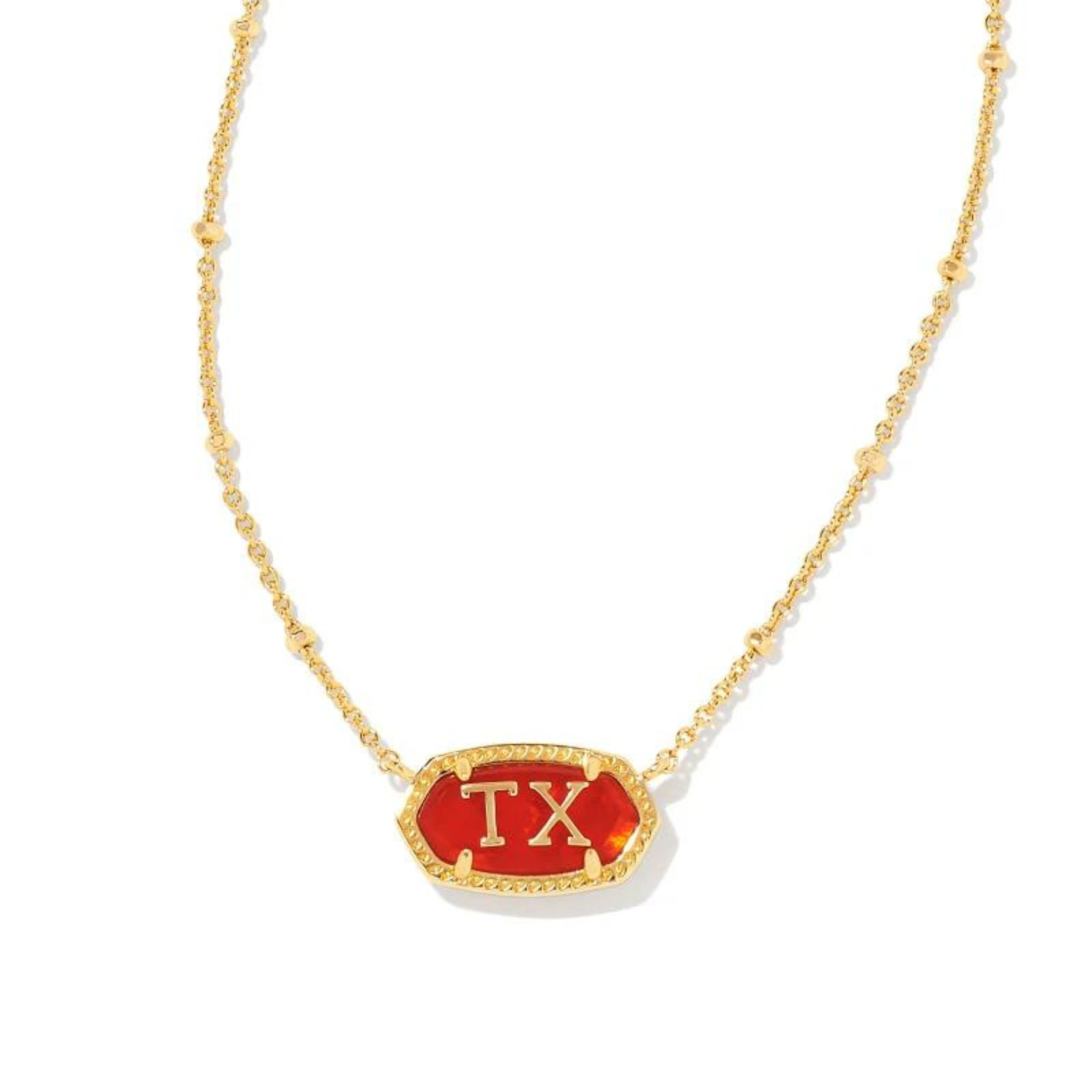 Pictured on a white background is a gold chain necklace with a red stone, oval pendant. This pendant has a gold outline and gold "TX" in the center.  