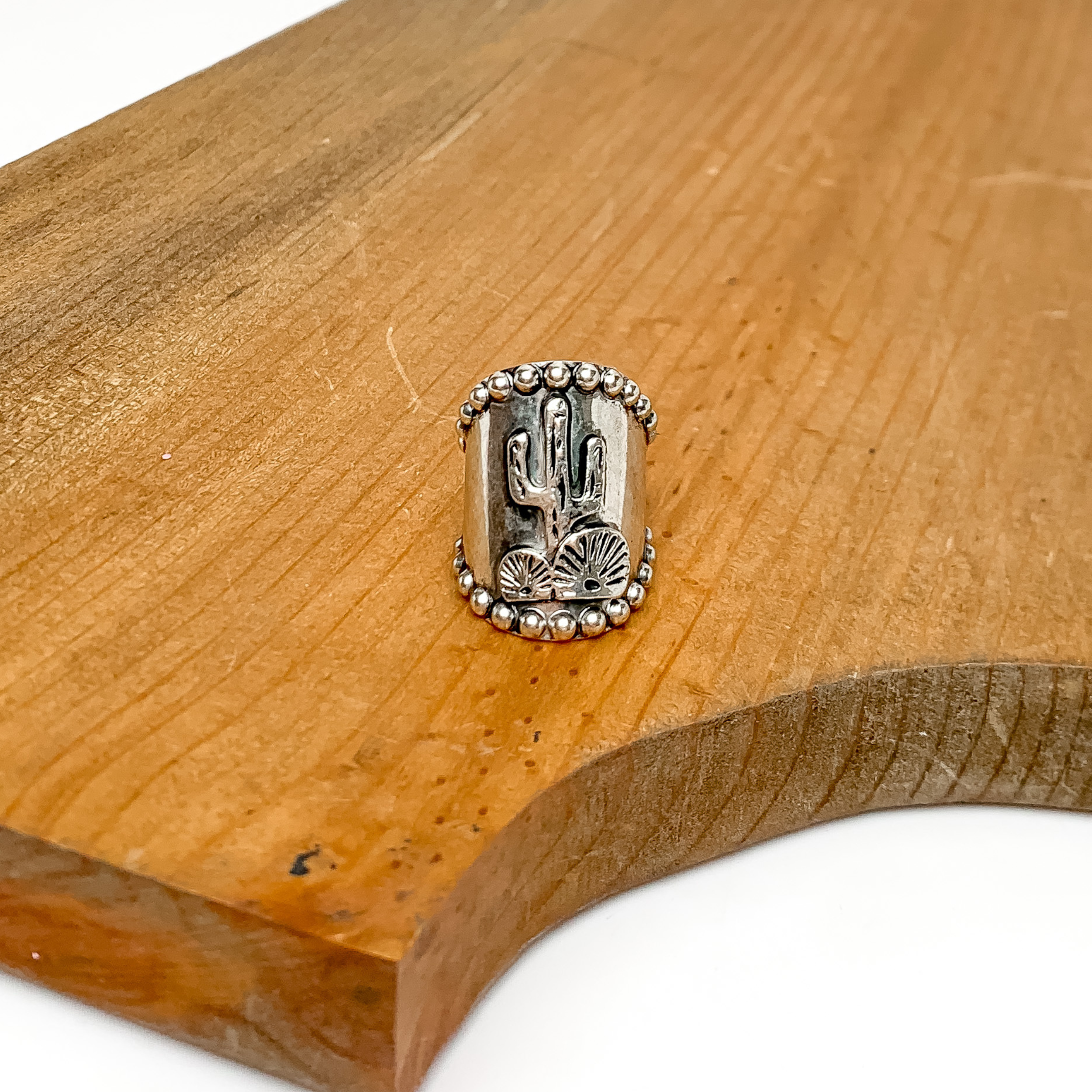 Silver Tone Desert Scene Cuff Ring. Pictured on a wood platform.