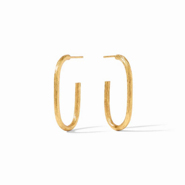 Gold oval hoop earrings pictured on a gold mirror. 