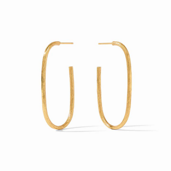 Gold oval hoop earrings pictured on a gold mirror. 