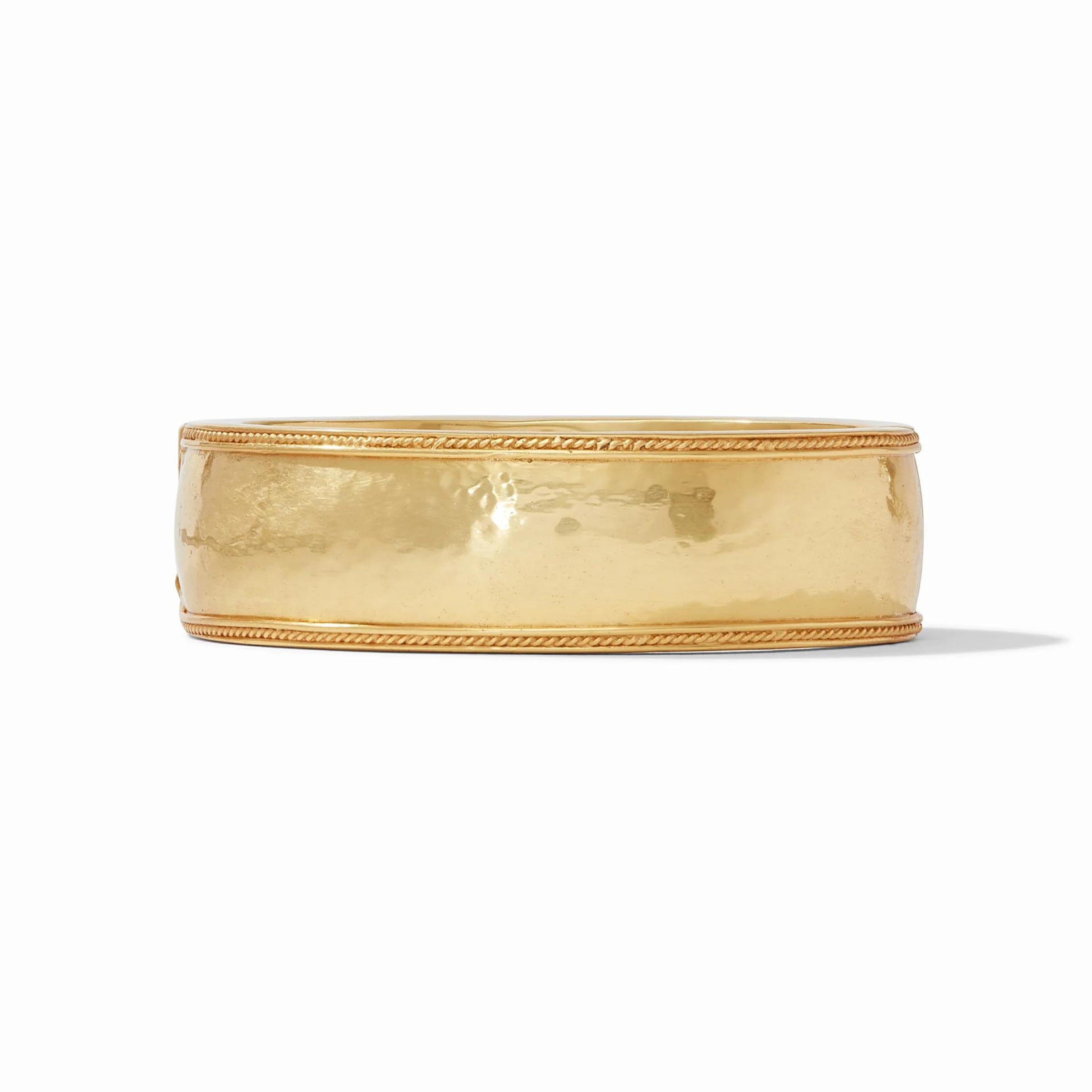 Gold, hammered bangle pictured on a white background. 