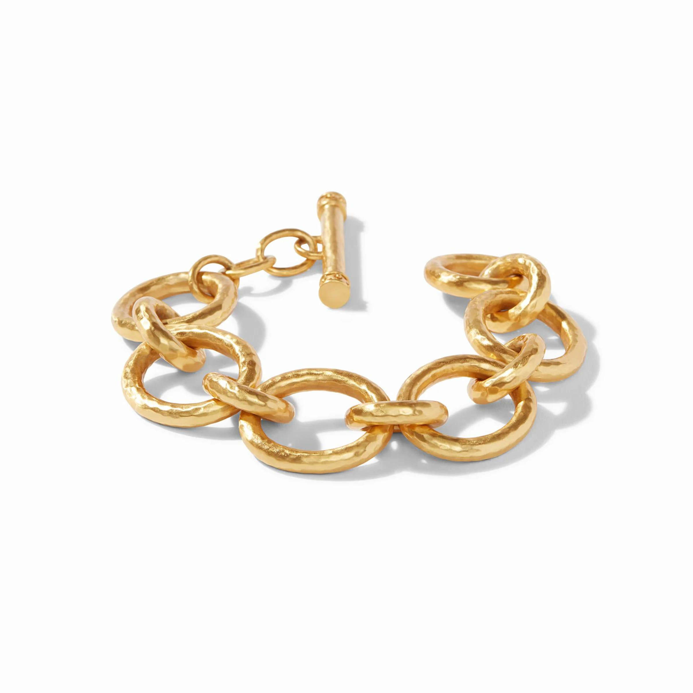 Gold, hammered chain link bracelet with toggle clasp pictured on a white background. 