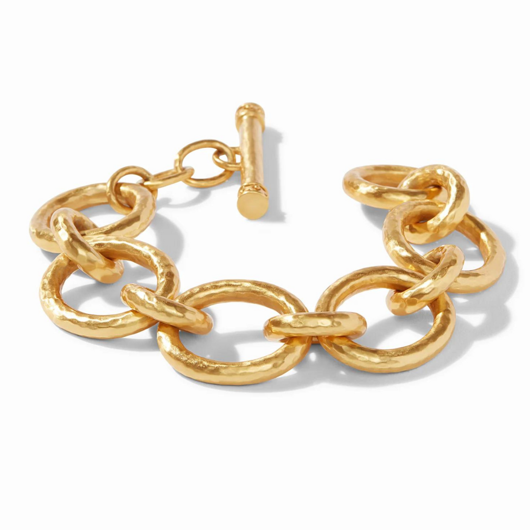 Gold, hammered chain link bracelet with toggle clasp pictured on a white background. 