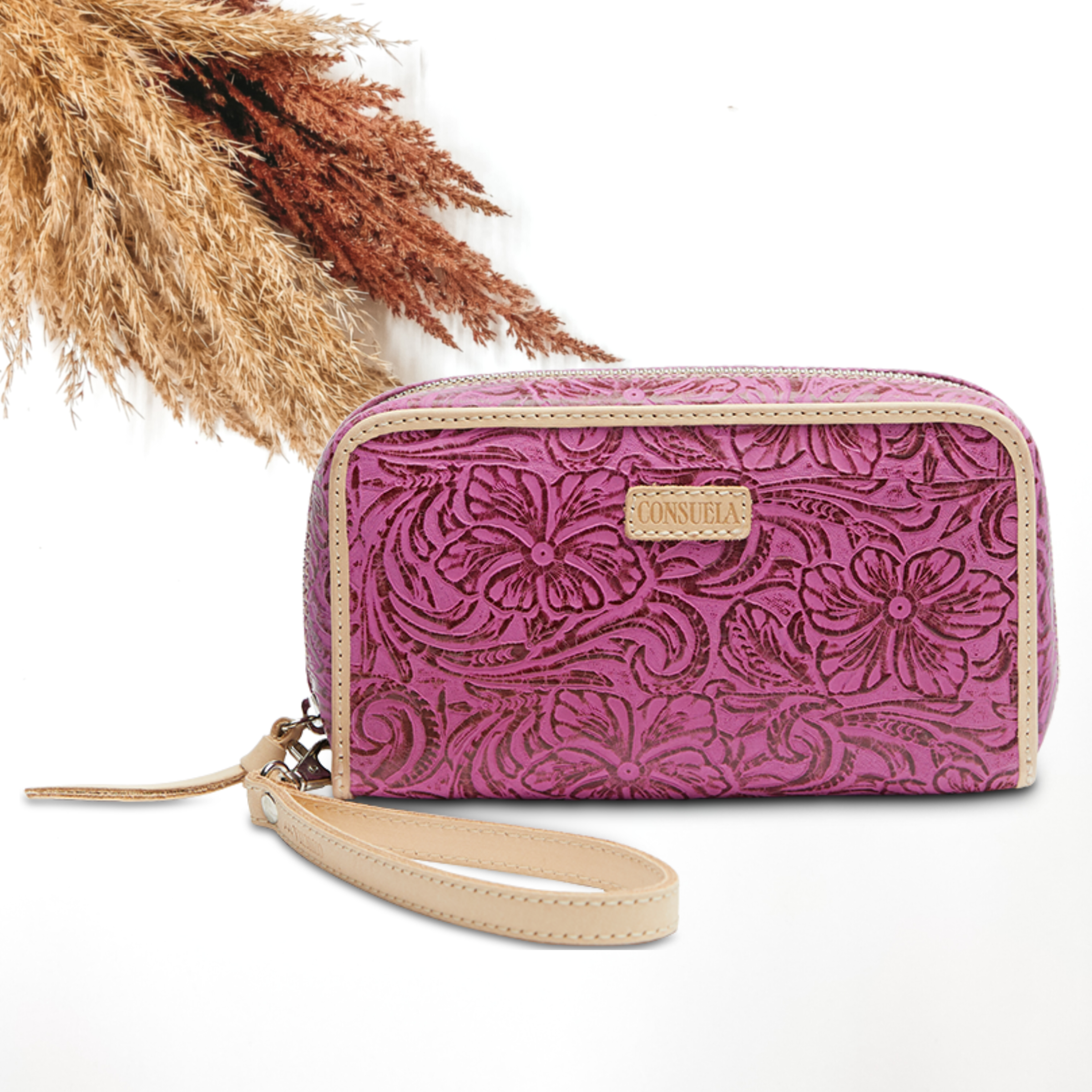 Pictured on a white background is a fuchsia, tooled leather print wristlet wallet. This wallet includes a light tan leather outline and wristlet.  