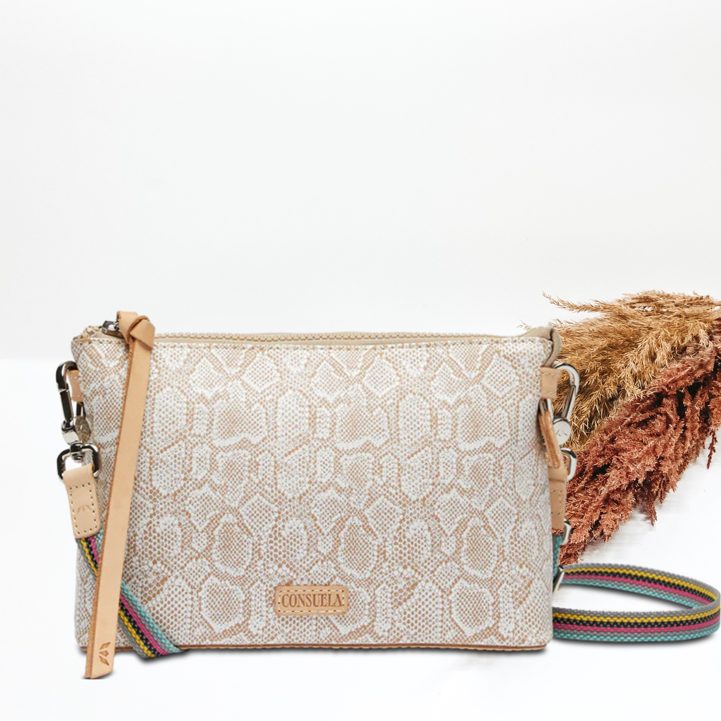 A white faux snake skin purse with a crossbody strap. Pictured on white background with brown pompous grass on the right side. 
