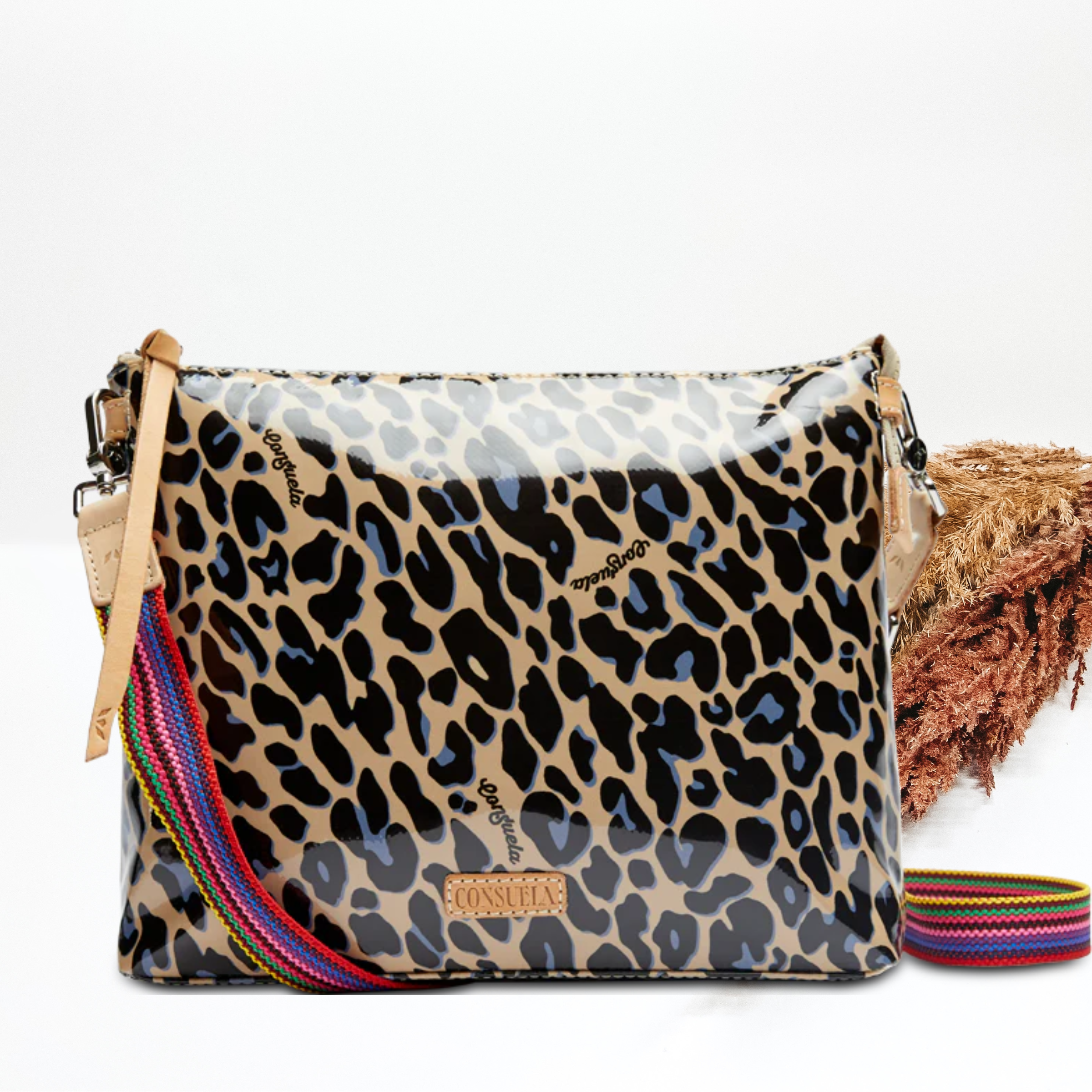 A leopard print purse with a crossbody strap. Pictured on white background with brown pompous grass on the right side. 