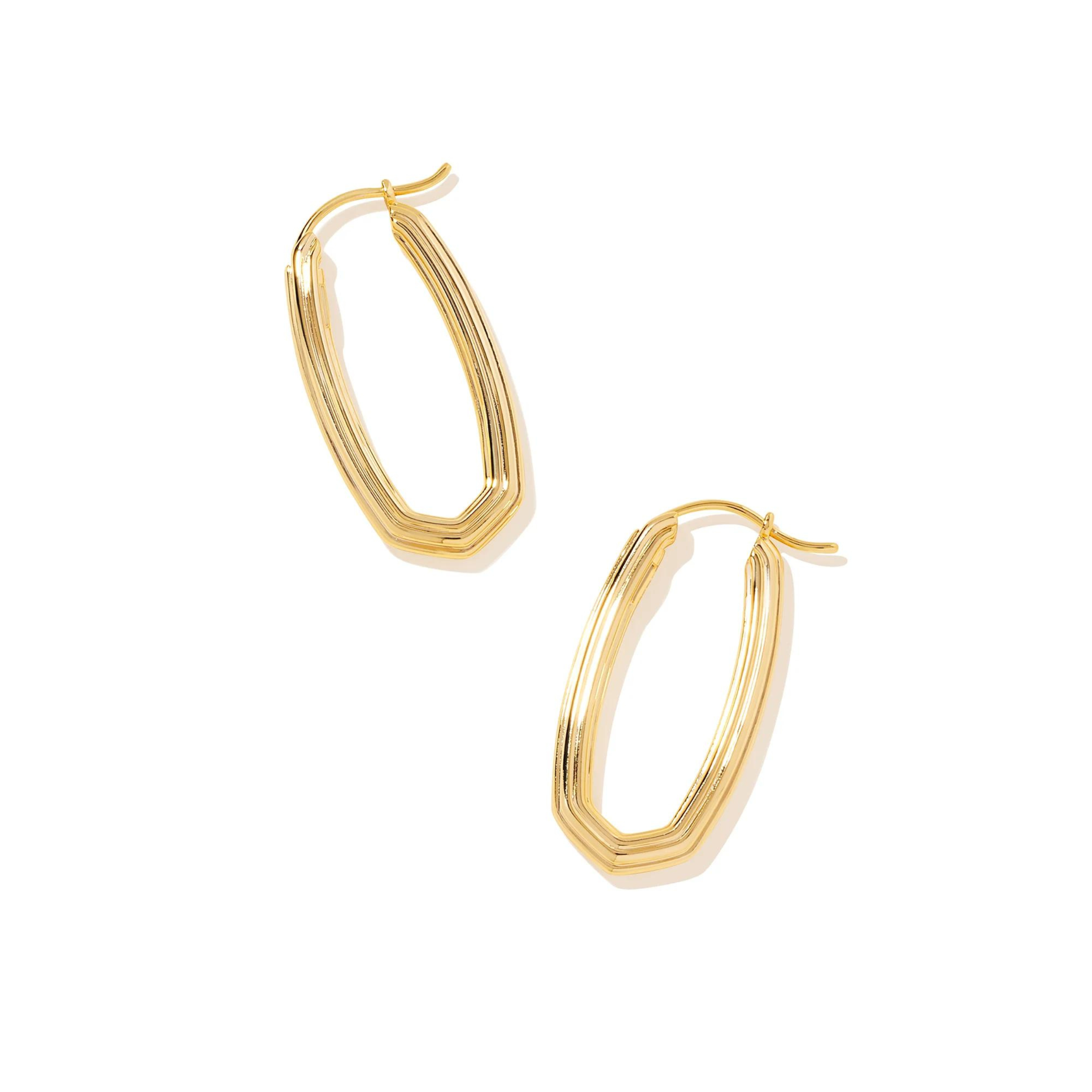 Pictured is a a pair of gold, oval, ridged texture hoops on a white background. 