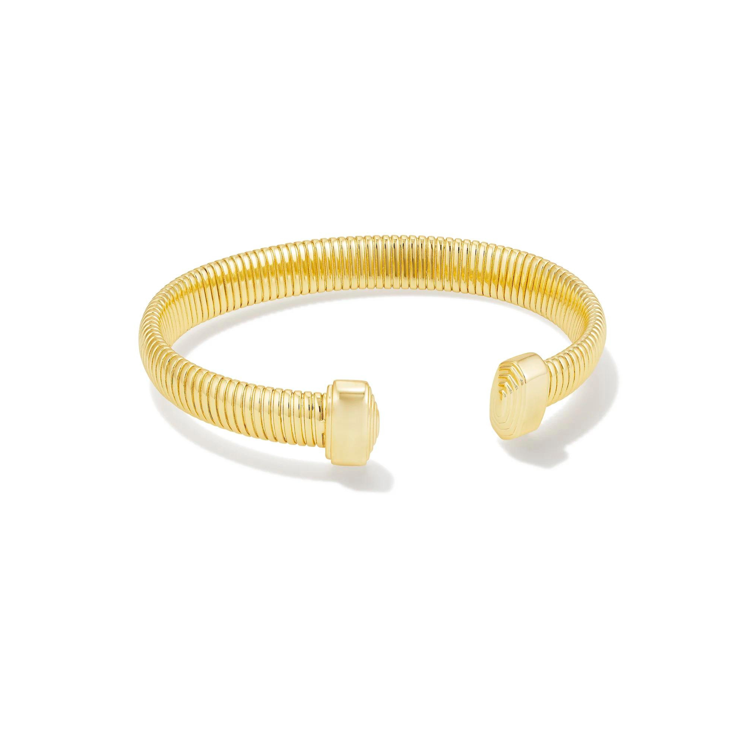 Pictured is a gold cuff bracelet with gold ends on a white background. 