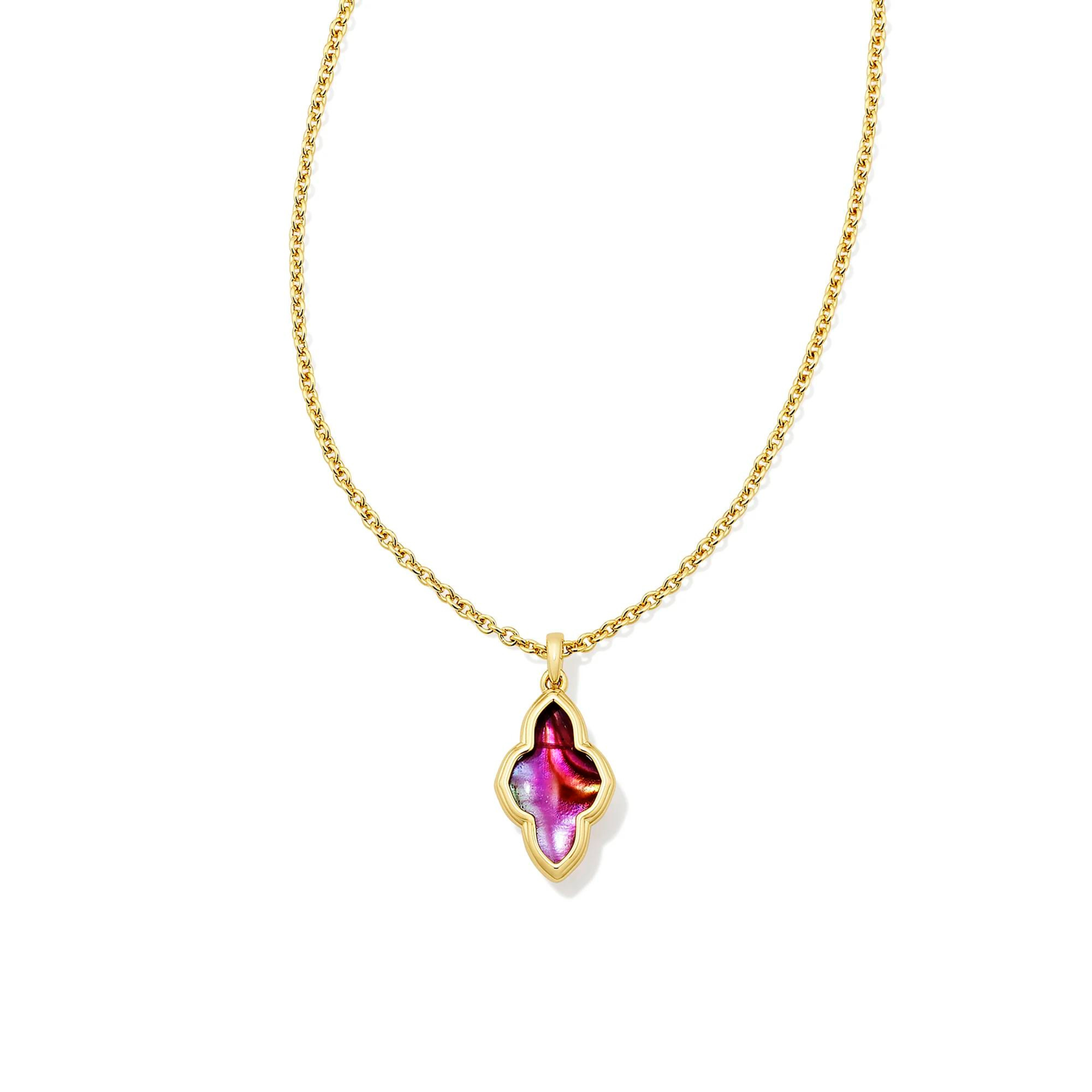 Pictured is a gold chain necklace with an abbie shaped necklace on a white background. This necklace includes a gold outline with a light burgundy illusion stone.  