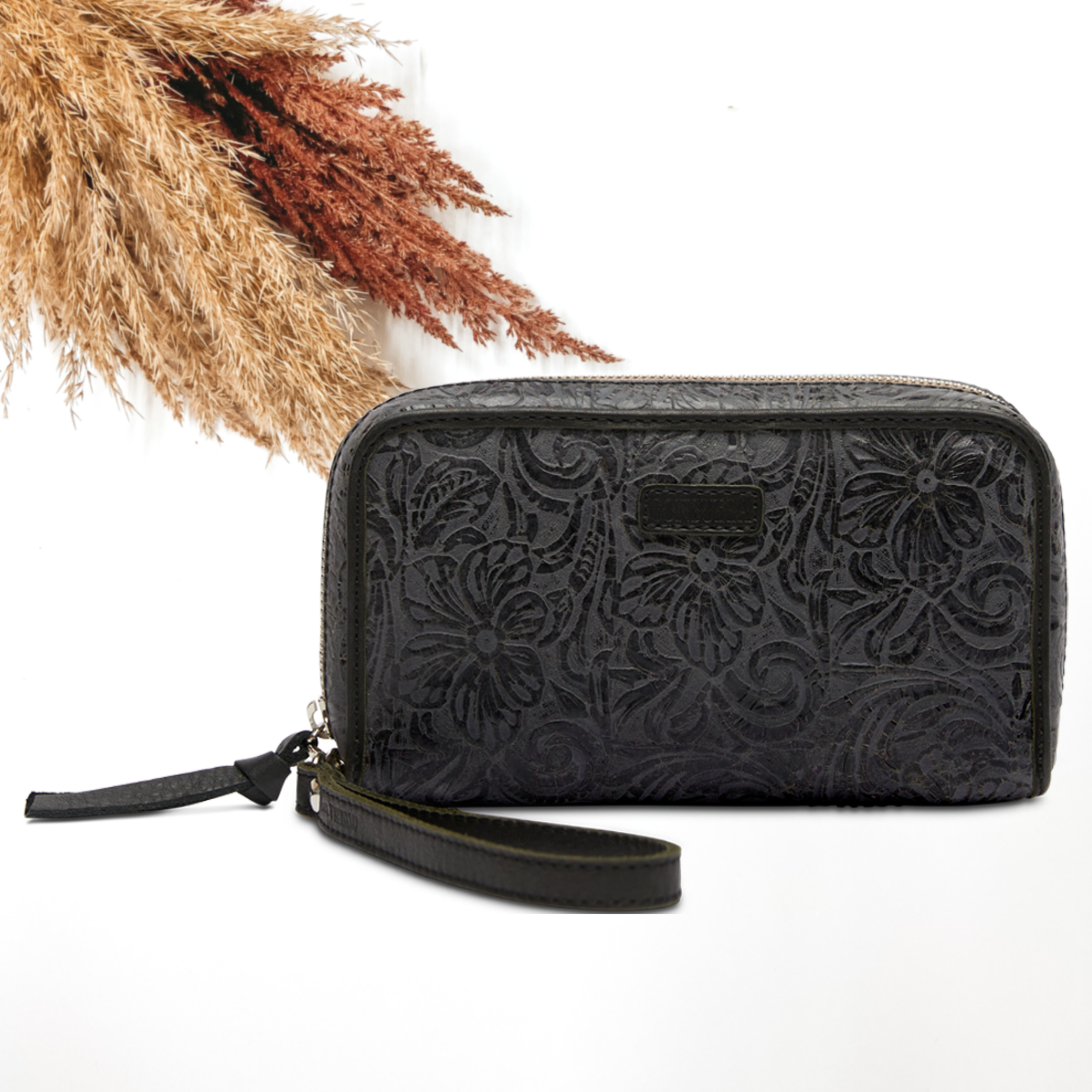 Pictured on a white background is a black, tooled leather print wristlet wallet. This wallet includes a black leather outline and wristlet.
