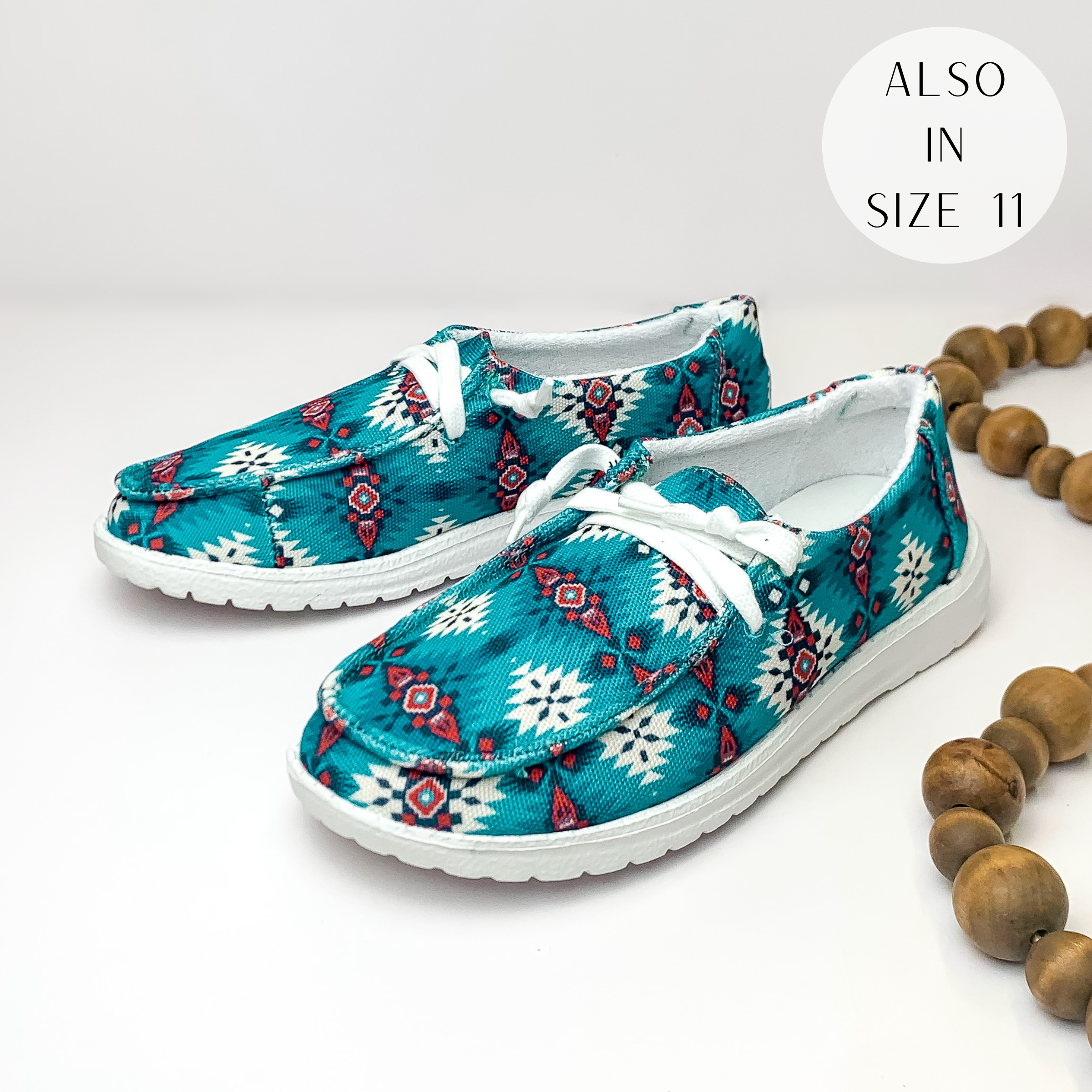 Blue shoes with a blue, white, and red aztec print and white laces. These shoes are pictured on a white background with brown beads on the right side.