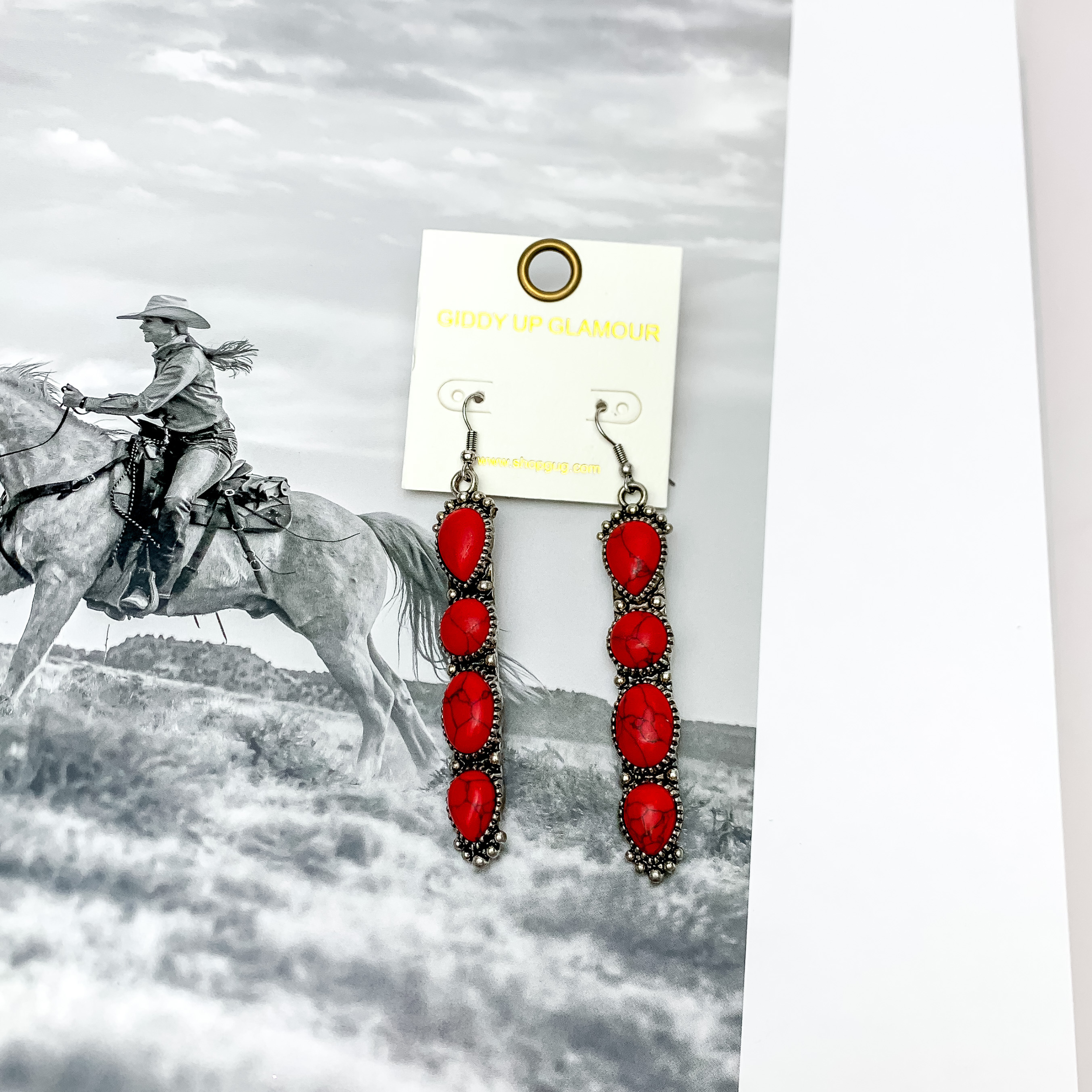 Western Connection Silver Tone Earrings With Four Stones in Red. Pictured with a western scene in the background.