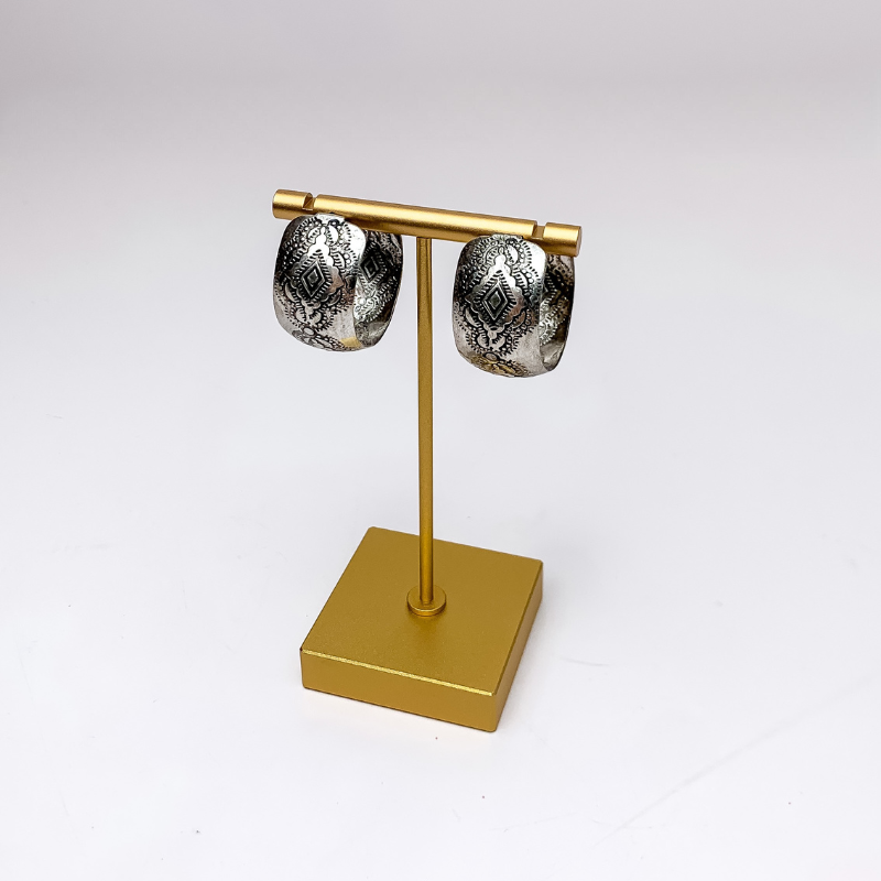 Western Silver Tone Thick Hoop Earrings. Pictured on a gold earring stand with a white background.