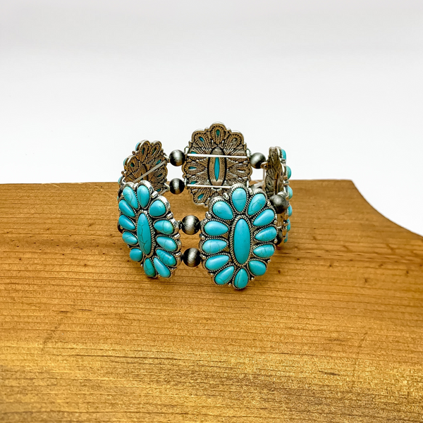 Western Concho Silver Tone Stretchy Bracelet in Turquoise. Pictured sitting on a wood piece with a white background.