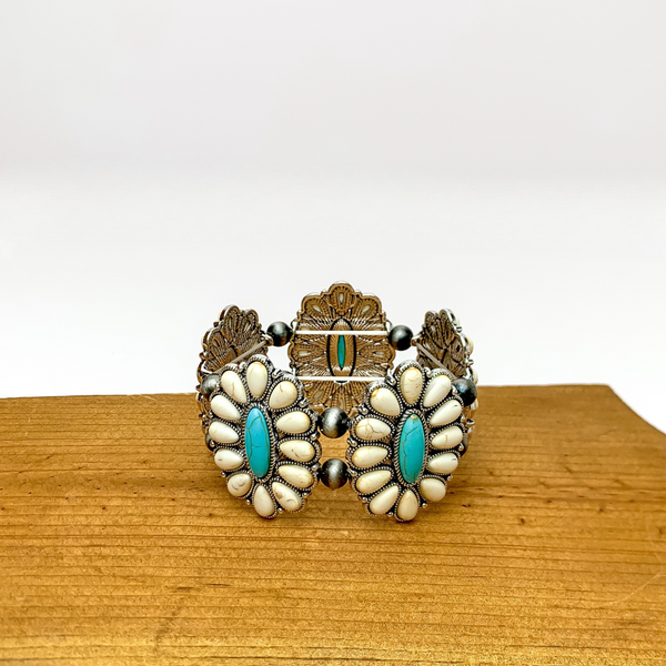 Western Concho Silver Tone Stretchy Bracelet in Turquoise and Ivory. Pictured sitting on a wood piece with a white background.