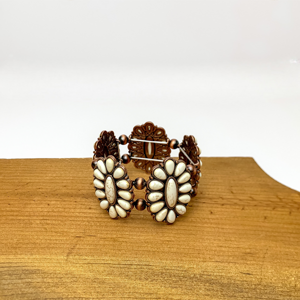 Western Concho Copper Tone Stretchy Bracelet in Ivory. Pictured sitting on a wood piece with a white background.