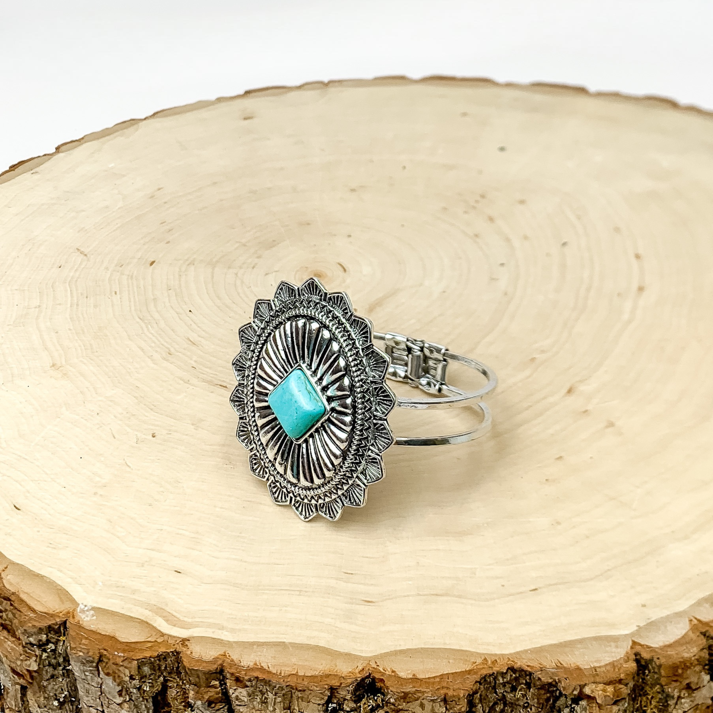 Western Oval Hinge Bracelet in Silver Tone With Turquoise Stone. Bracelet is pictured on a piece of wood with a white background behind it.