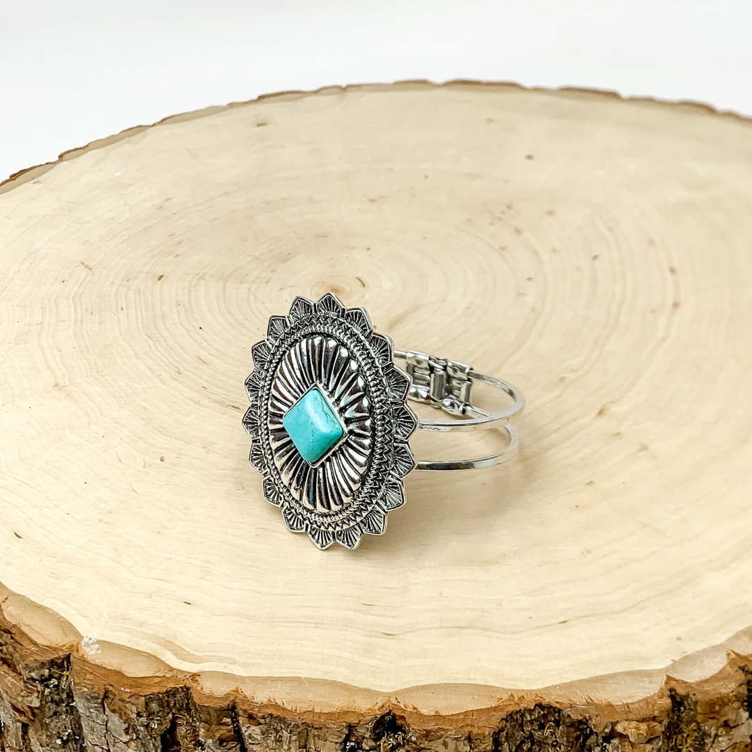 Western Oval Hinge Bracelet in Silver Tone With Turquoise Stone. Bracelet is pictured on a piece of wood with a white background behind it.