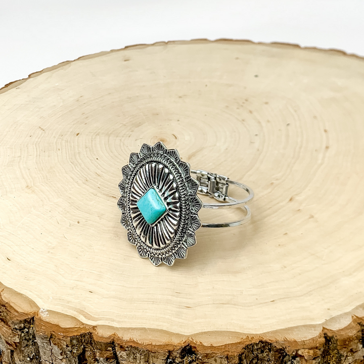 Western Oval Hinge Bracelet in Silver Tone With Turquoise Stone. Bracelet is pictured on a piece of wood with a white background behind it.