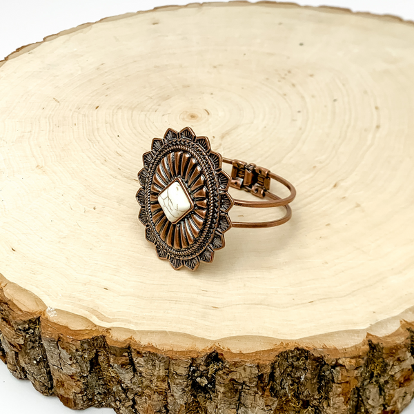 Western Oval Hinge Bracelet in Copper Bronze With Ivory Stone. Pictured on a slab of wood.