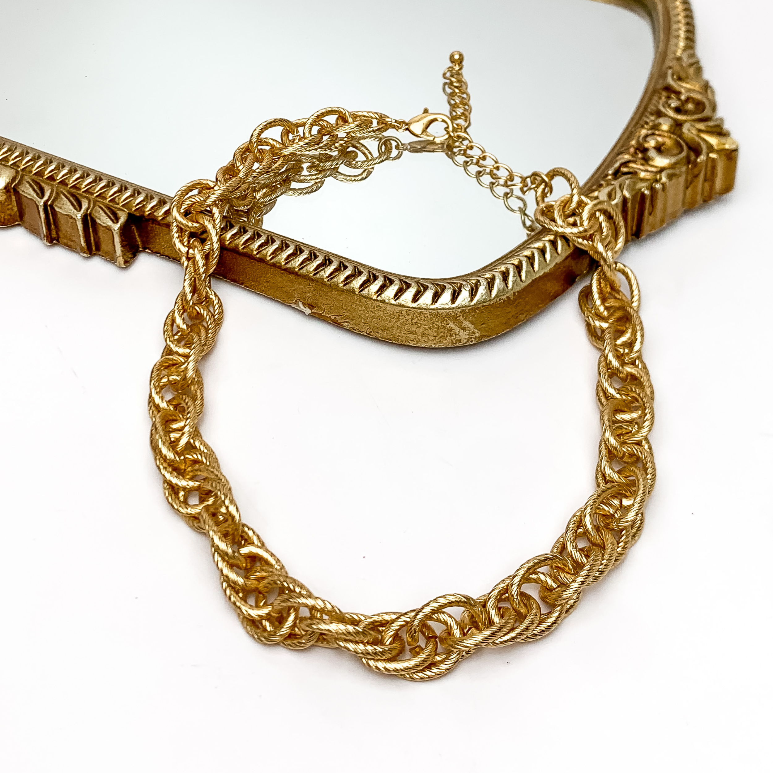 Back To Basics Gold Tone Chain Necklace. Pictured on a white background with part of the necklace laying on a gold frame mirror.