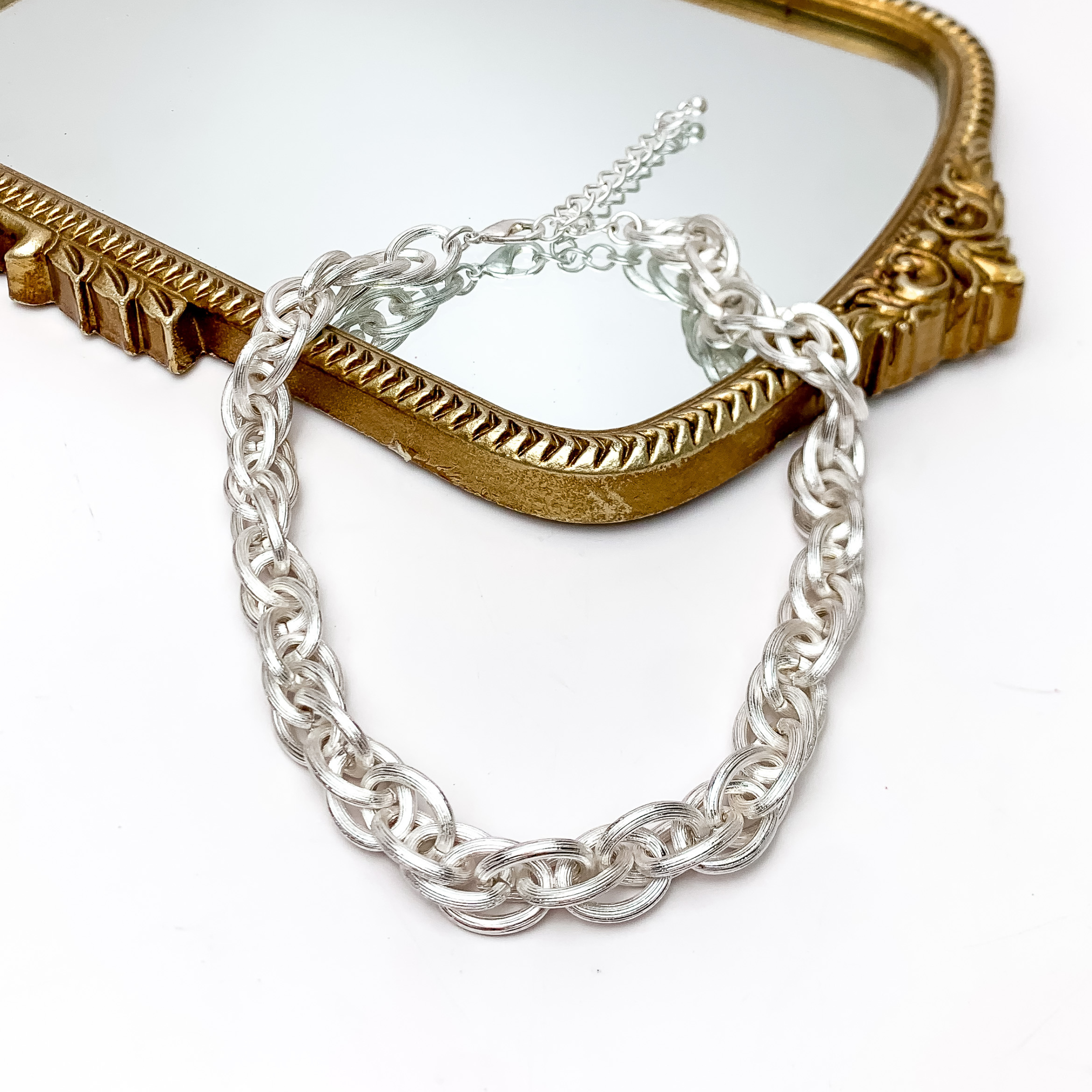 Back To Basics Silver Tone Chain Necklace. Pictured on a white background with part of the necklace laying on a gold frame mirror.