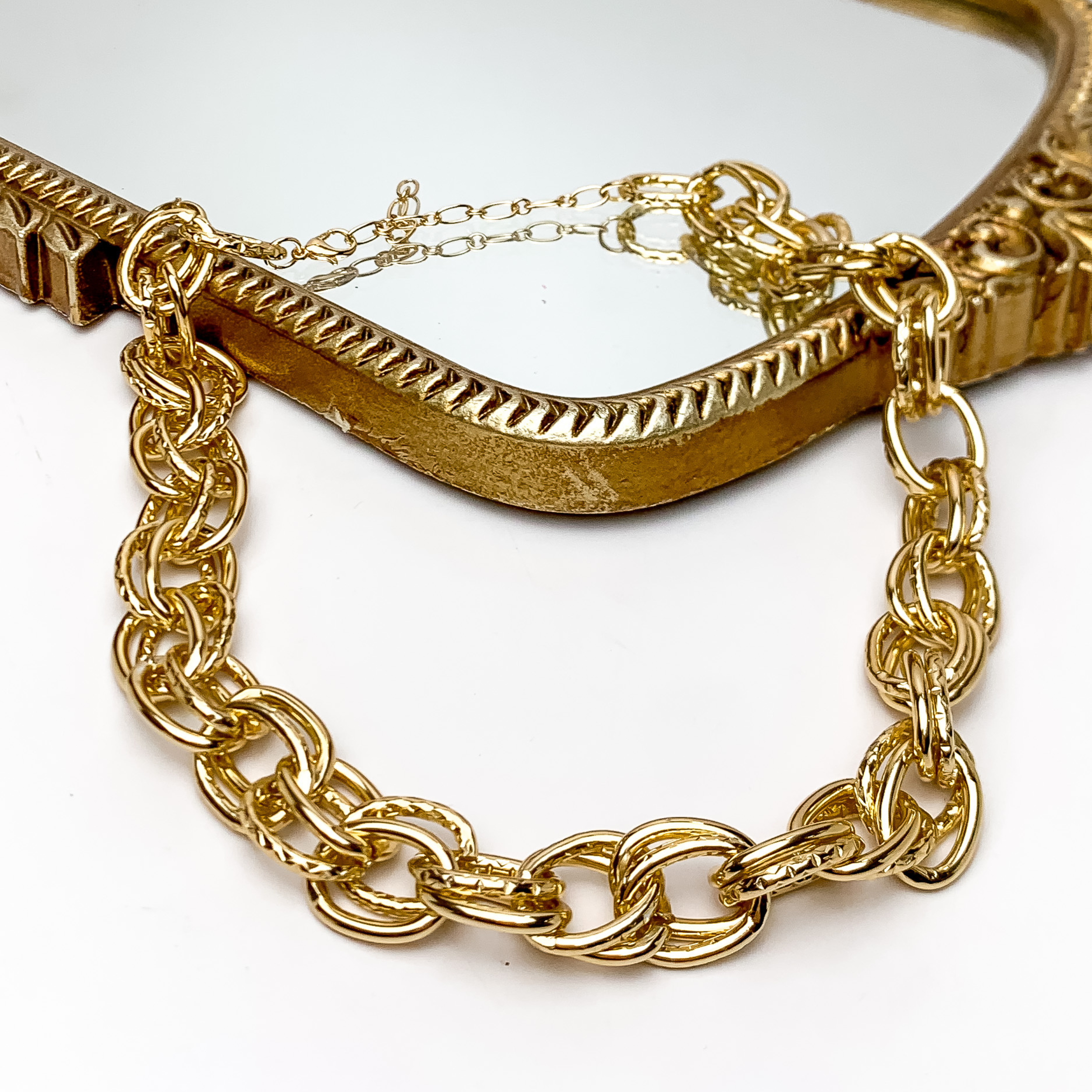 Classic Chunky Gold Tone Chain Necklace. Pictured on a white background with part of the necklace on a gold trimmed mirror.