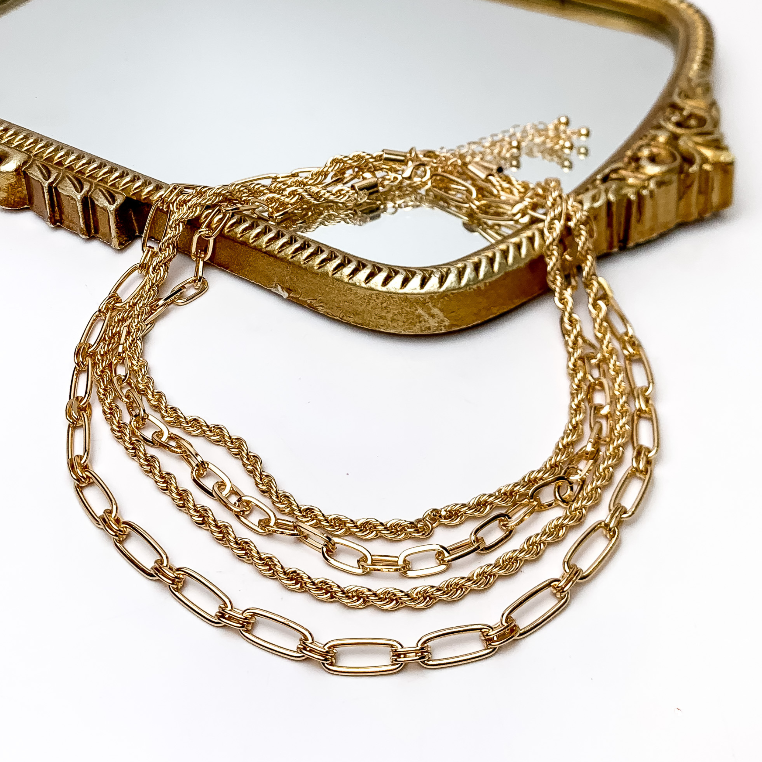 Sunday Style Gold Tone Chain Necklace. Pictured on a white background with part of the necklace on a gold framed mirror.