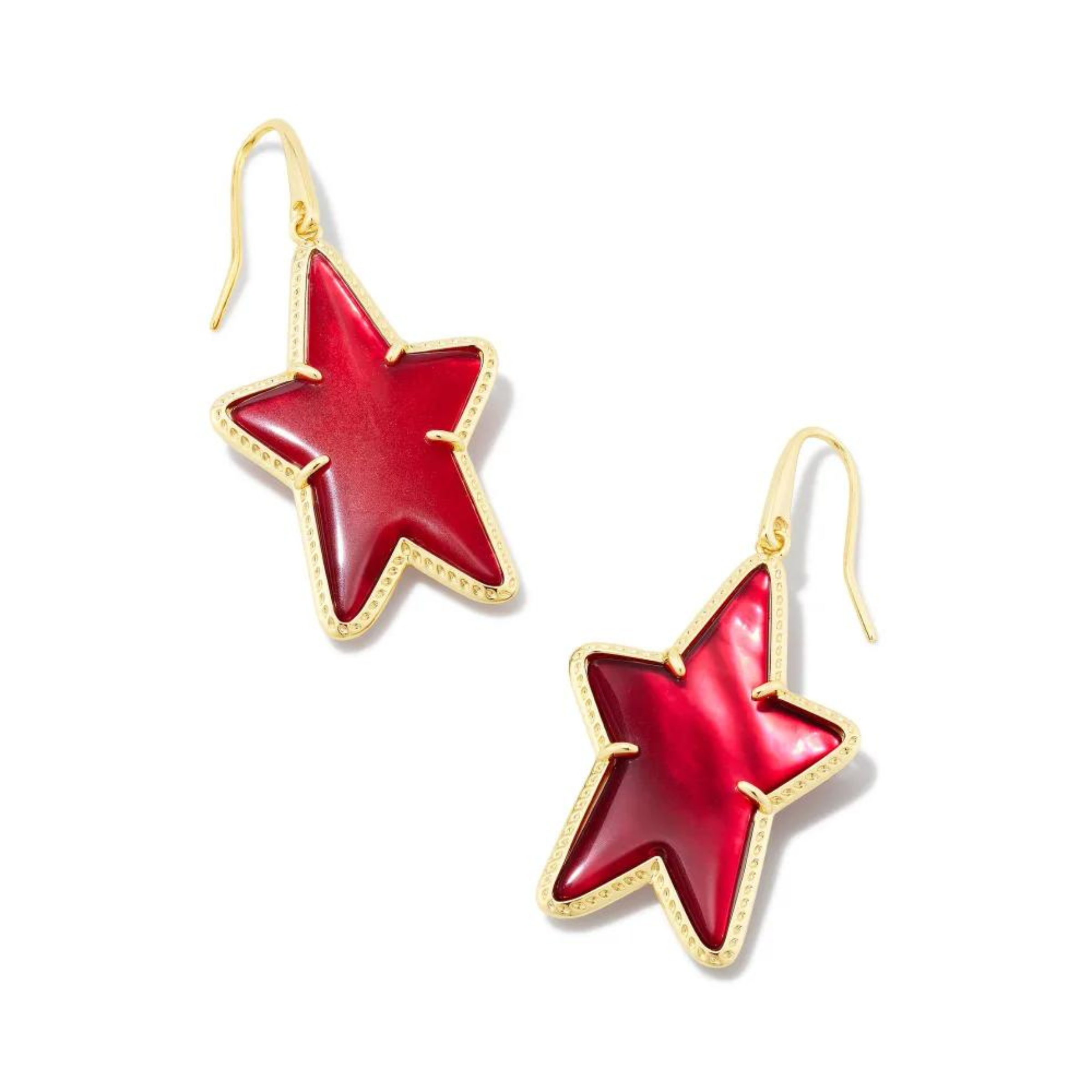 Pictured on a white background are gold fish hook earrings with a gold star dangle that includes a red colored star shaped stone. 
