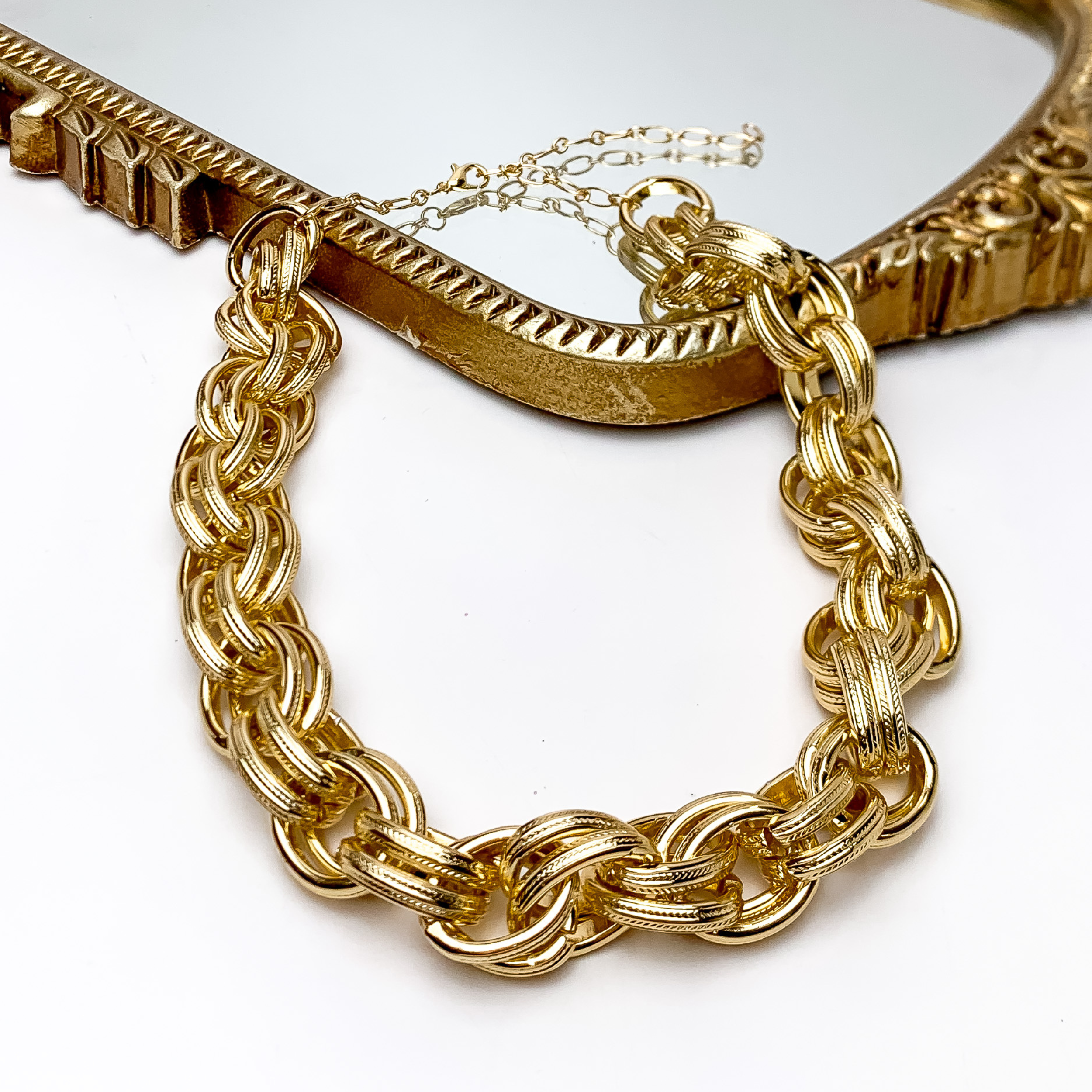 Night Out Gold Tone Chunky Chain Necklace. Pictured on a white background with part of then necklace on a gold trimmed mirror.