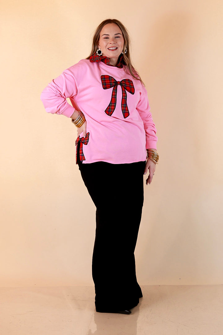 All Wrapped Up pink crewneck sweatshirt front view showing the large plaid bow and side slit bow detail