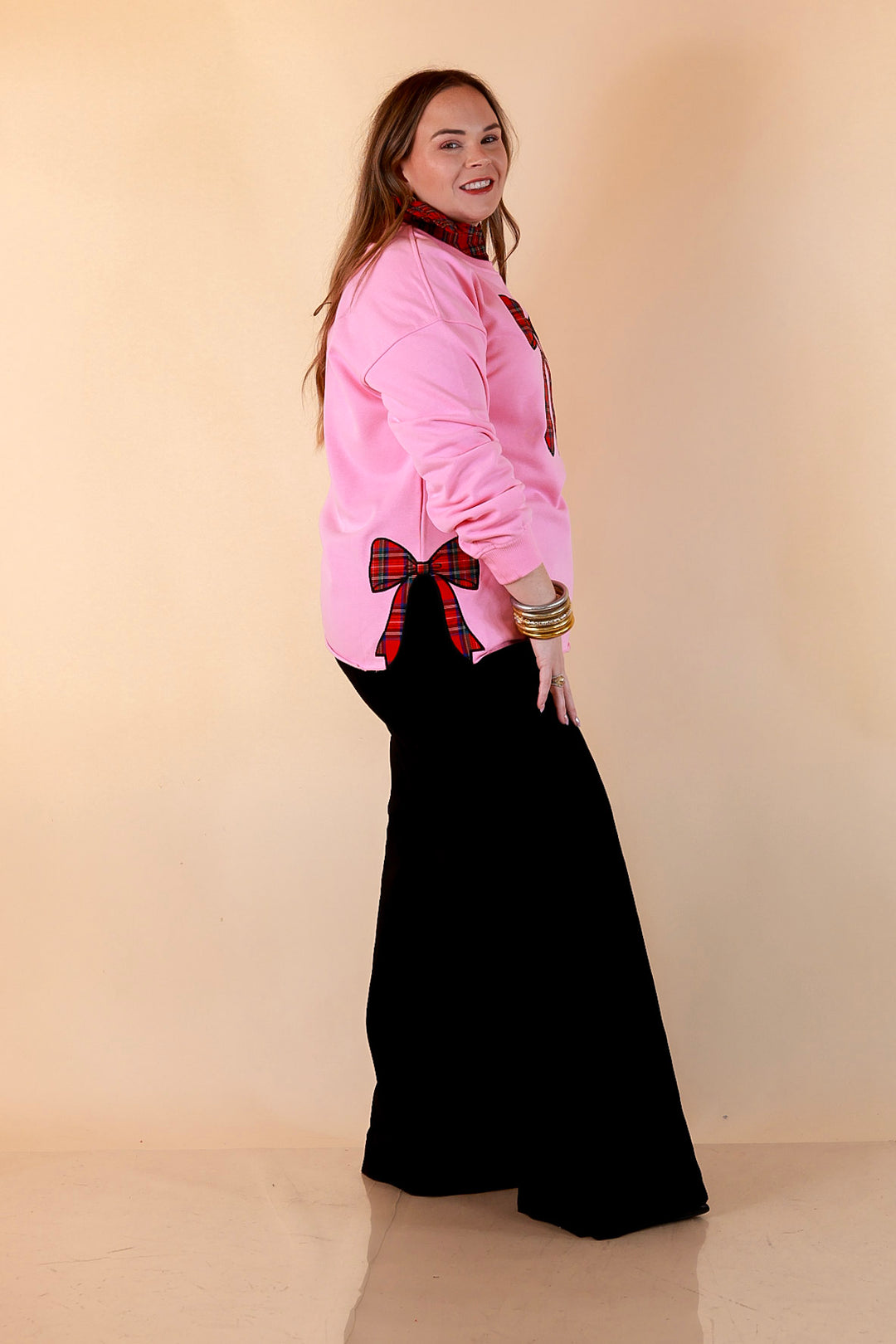 All Wrapped Up pink sweatshirt side view showing the red plaid bow appliqué at the side slit