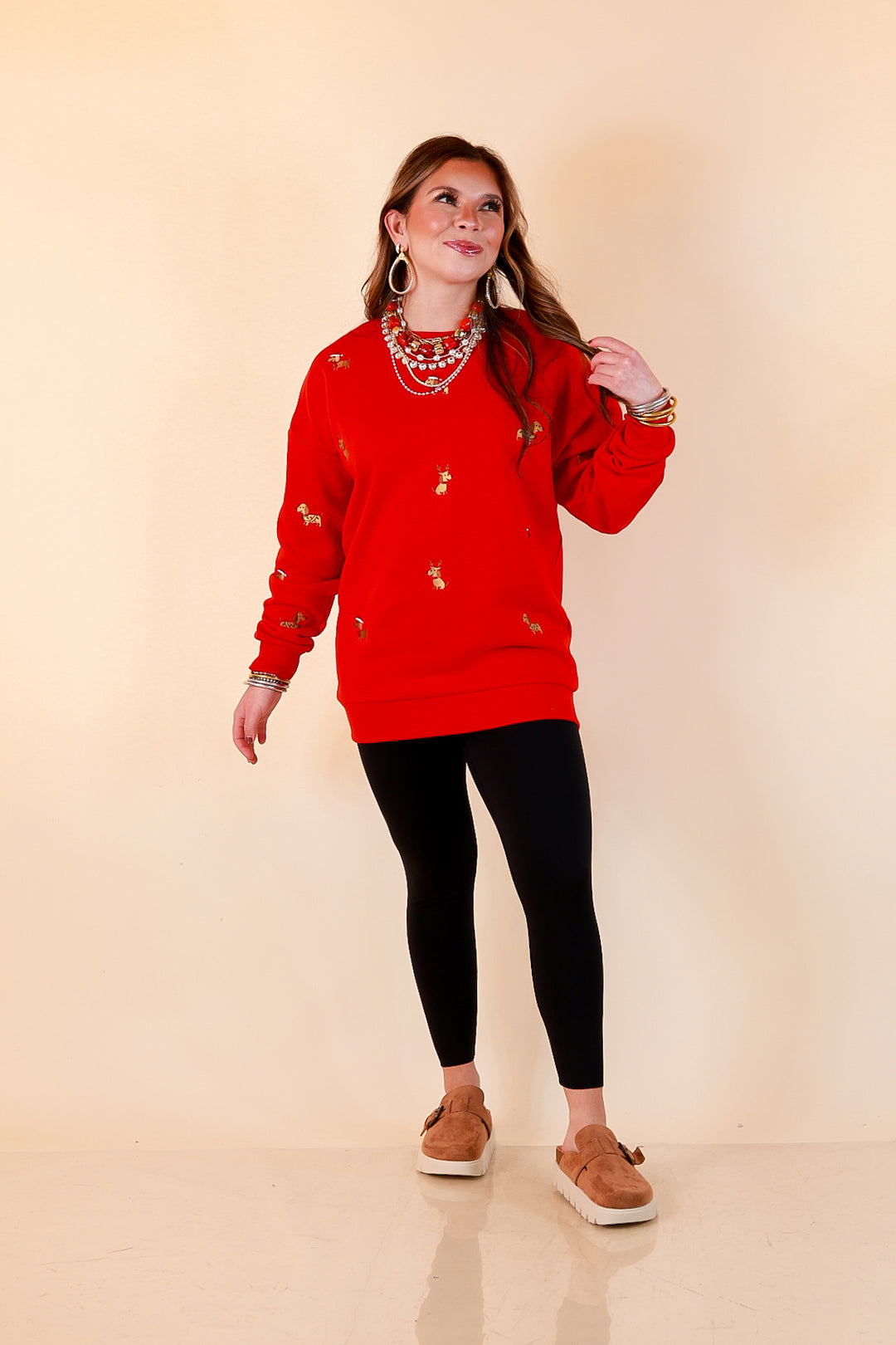 Best in Show red crewneck sweatshirt with allover embroidered holiday dogs, styled with black leggings and tan clogs