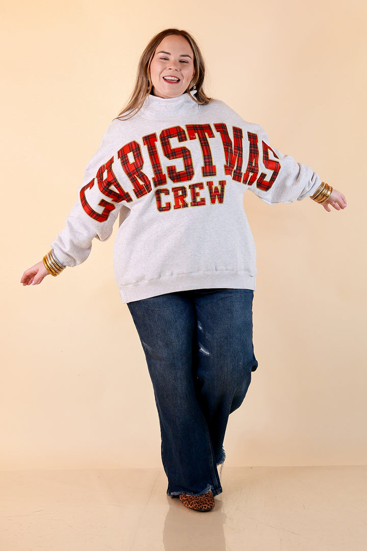 Plaid Tidings heather gray oversized mock neck sweatshirt with red plaid Christmas Crew lettering outlined in gold, styled with dark wash jeans