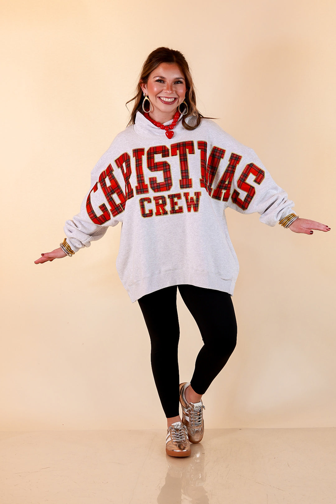 Plaid Tidings heather gray oversized mock neck sweatshirt with red plaid Christmas Crew lettering across the front and sleeves, styled with black leggings and metallic sneakers