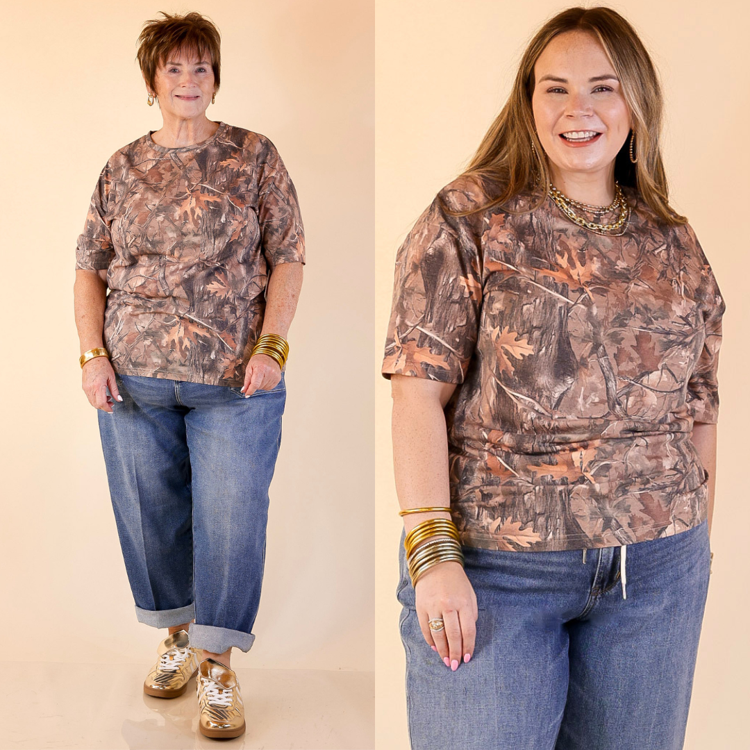 Two women wearing camouflage shirts and jeans on a beige background