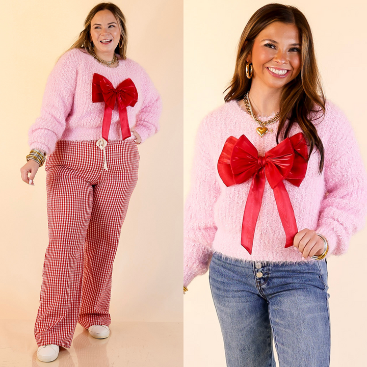 Models are wearing a pink sweater with a red bow, one in gingham checkered pants and the other in jeans.