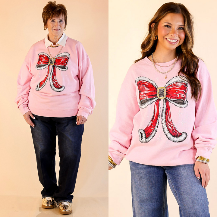 Models are wearing pink sweatshirts with a large red bow design on a beige background.