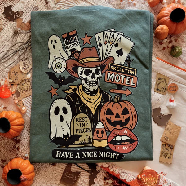T-shirt with Halloween-themed design featuring a skeleton, ghosts, and pumpkins on a textured surface.