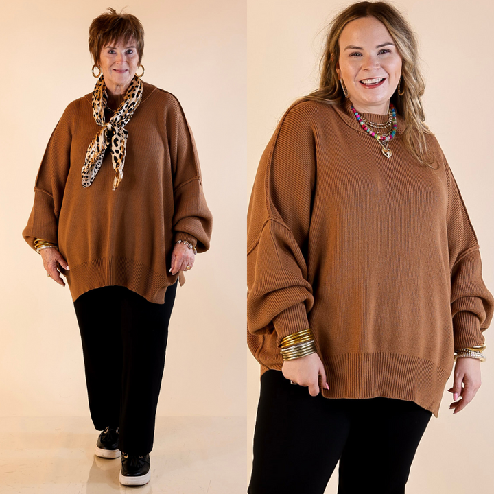Models are wearing camel brown oversized sweater with side slit. One model is showcasing a smaller size while the other is wearing a larger size, both in combination with black pants and flat shoes.