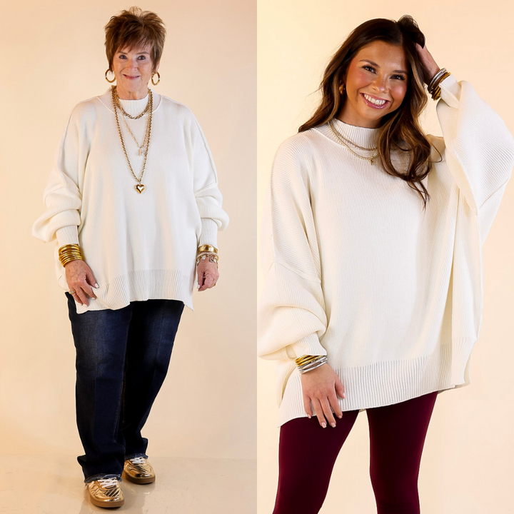 Models are wearing ivory oversized sweater with side slit. One model is showcasing a smaller size while the other is wearing a larger size.