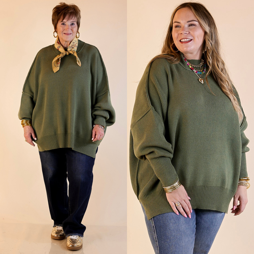 Models are wearing olive green oversized sweater with side slit. One model is showcasing a smaller size while the other is wearing a larger size, with jeans. 