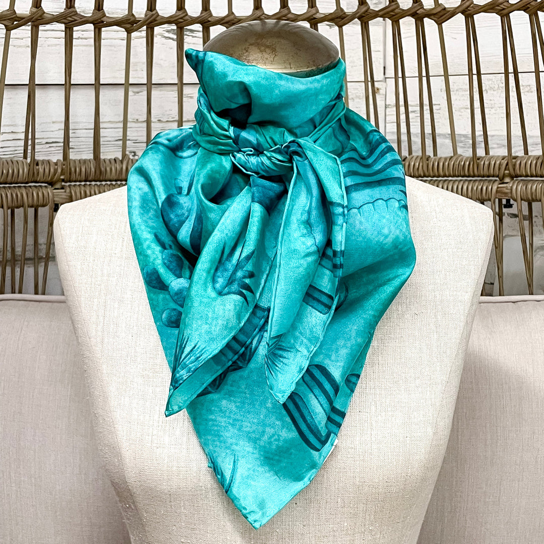 Turquoise scarf tied around a mannequin head against a neutral background