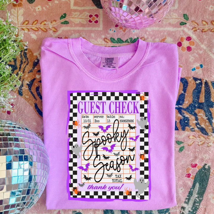 Folded purple shirt with Halloween-themed design on a patterned surface
