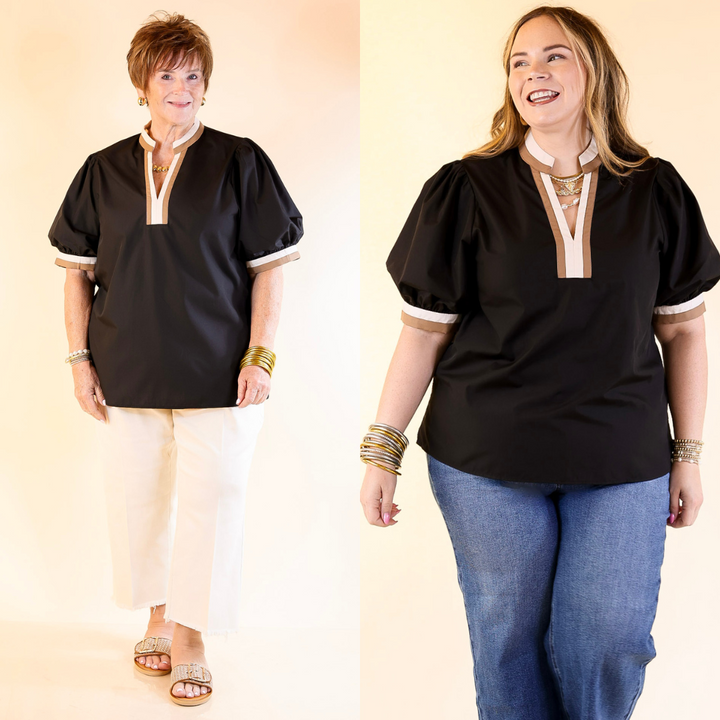 Two women wearing black tops with white trim against a plain background
